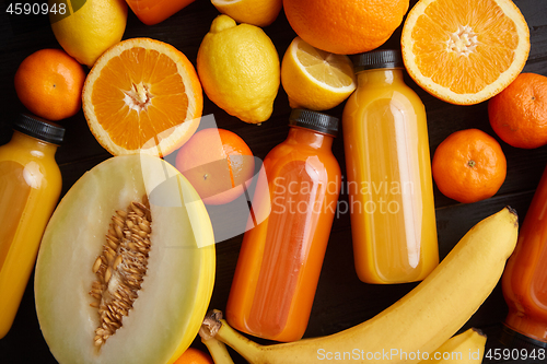Image of Mix of orange and yellow colored fruits and juices on black wood