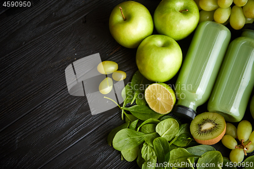 Image of Mixed green fruits and vegetables placed on black wooden table