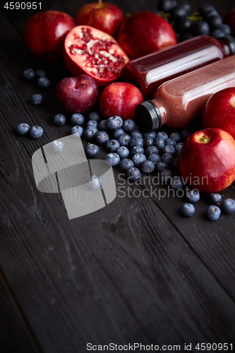 Image of Various fresh red, purple black fruits. Mix of fruits and bottle