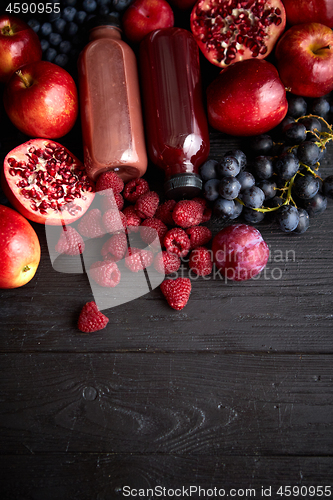 Image of Various fresh red, purple black fruits. Mix of fruits and bottle