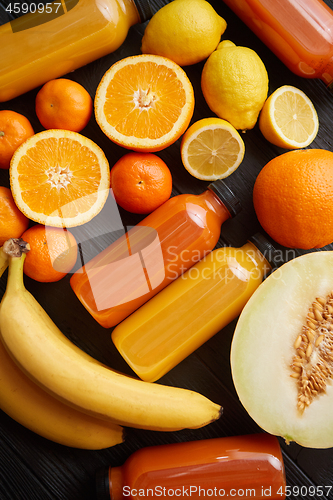 Image of Mix of orange and yellow colored fruits and juices on black wood