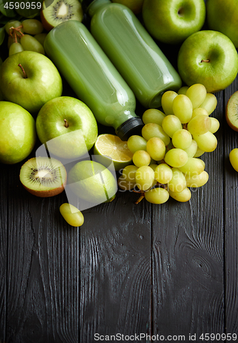 Image of Mixed green fruits and vegetables placed on black wooden table