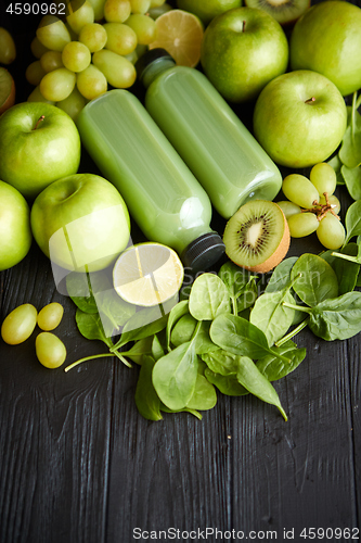 Image of Mixed green fruits and vegetables placed on black wooden table