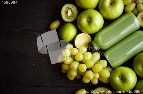 Image of Mixed green fruits and vegetables placed on black wooden table