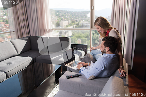 Image of couple relaxing at  home using laptop computers