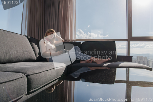 Image of young woman on sofa at home surfing web