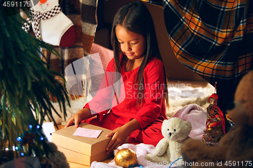 Image of Merry Christmas and Happy Holidays. Cute little child girl writes the letter to Santa Claus near Christmas tree