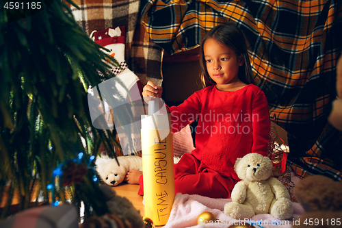 Image of Merry Christmas and Happy Holidays. Cute little child girl writes the letter to Santa Claus near Christmas tree