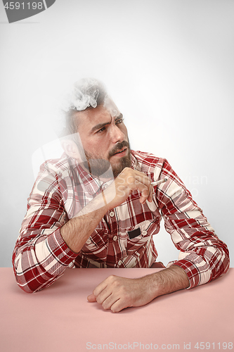 Image of Handsome hipster man smoking cigarette at home. Man looking upwards and enjoying spending free time.