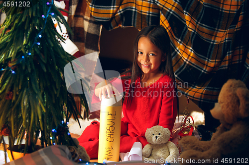 Image of Merry Christmas and Happy Holidays. Cute little child girl writes the letter to Santa Claus near Christmas tree