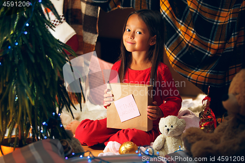 Image of Merry Christmas and Happy Holidays. Cute little child girl writes the letter to Santa Claus near Christmas tree