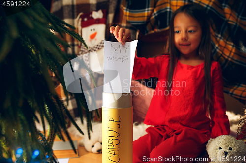 Image of Merry Christmas and Happy Holidays. Cute little child girl writes the letter to Santa Claus near Christmas tree