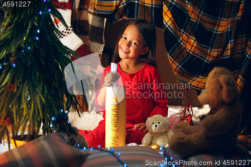 Image of Merry Christmas and Happy Holidays. Cute little child girl writes the letter to Santa Claus near Christmas tree