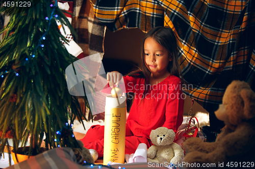 Image of Merry Christmas and Happy Holidays. Cute little child girl writes the letter to Santa Claus near Christmas tree