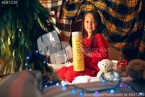 Image of Merry Christmas and Happy Holidays. Cute little child girl writes the letter to Santa Claus near Christmas tree