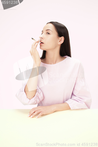 Image of Handsome young women smoking while sitting at table at studio. Trendy colors