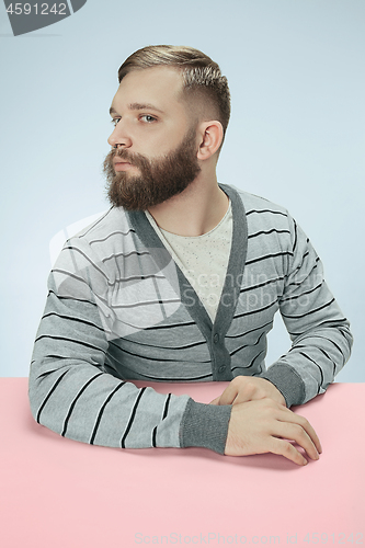 Image of Serious business man sitting at a table on a blue background