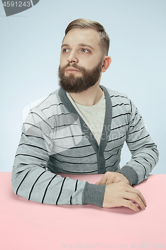 Image of Serious business man sitting at a table on a blue background