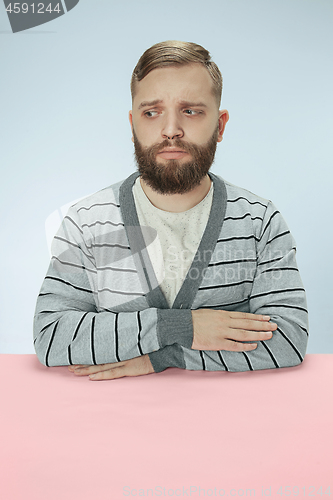 Image of Serious business man sitting at a table on a blue background