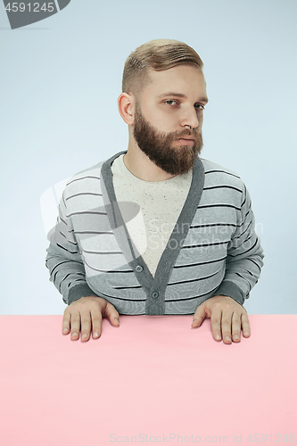 Image of Serious business man sitting at a table on a blue background