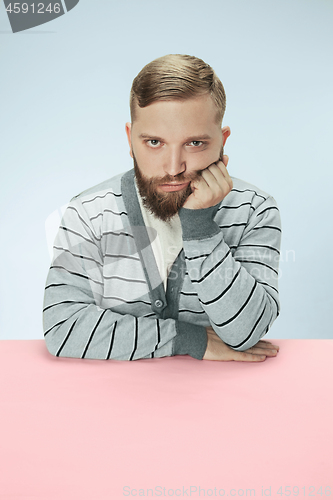 Image of Serious business man sitting at a table on a blue background