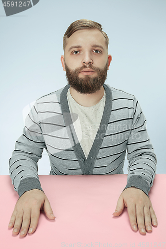 Image of Serious business man sitting at a table on a blue background