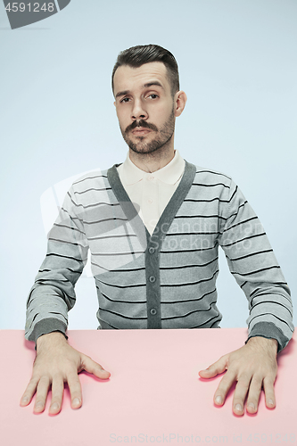 Image of Serious business man sitting at a table on a blue background