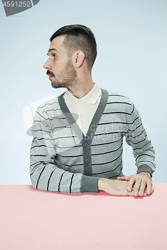 Image of Serious business man sitting at a table on a blue background