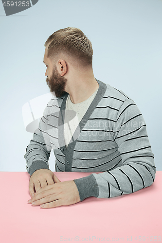 Image of Serious business man sitting at a table on a blue background