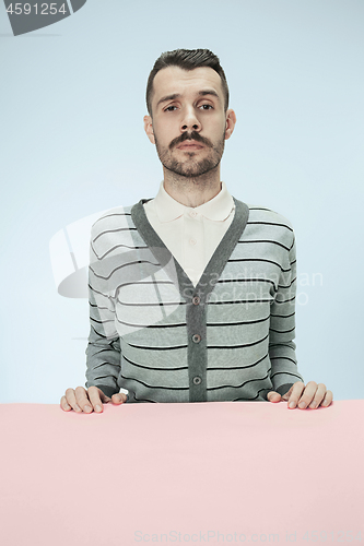 Image of Serious business man sitting at a table on a blue background