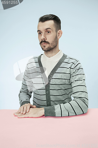 Image of Serious business man sitting at a table on a blue background