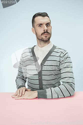 Image of Serious business man sitting at a table on a blue background