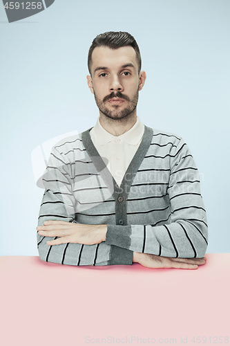 Image of Serious business man sitting at a table on a blue background