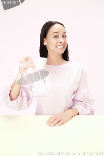 Image of Beautiful lonely woman sitting at studio and looking happy holding the cup of coffee in hand. Closeup toned portrait