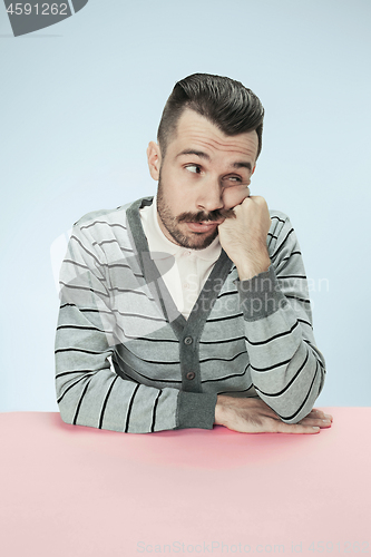 Image of Serious business man sitting at a table on a blue background