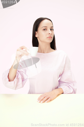 Image of Beautiful lonely woman sitting at studio and looking sad holding the cup of coffee in hand. Closeup toned portrait