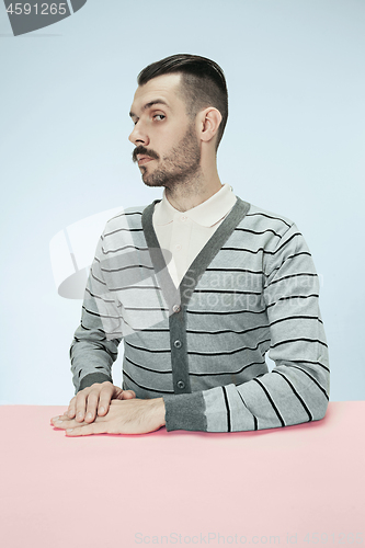 Image of Serious business man sitting at a table on a blue background