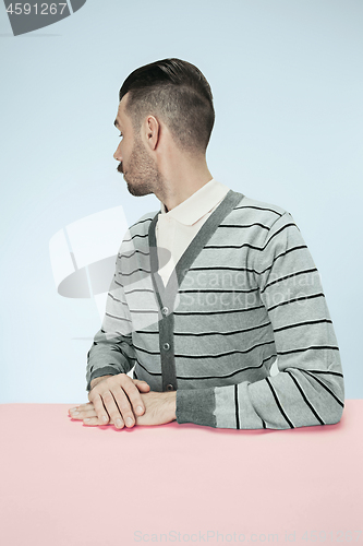 Image of Serious business man sitting at a table on a blue background