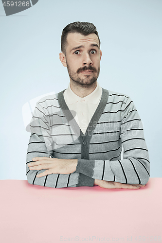 Image of Surprised business man sitting at a table on a blue background