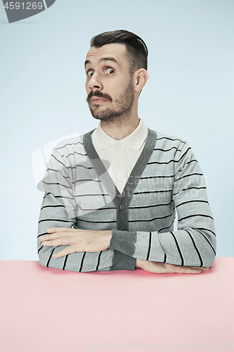 Image of Surprised business man sitting at a table on a blue background