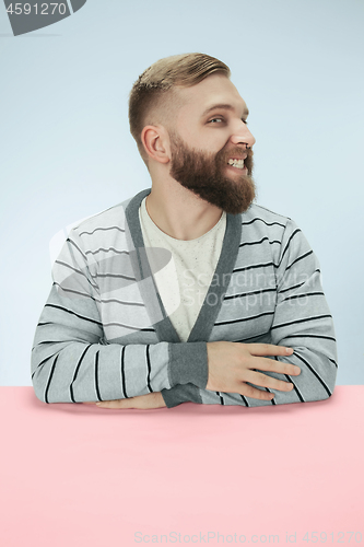 Image of The happy smiling businessman sitting at a table on a blue background