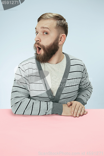 Image of Surprised business man sitting at a table on a blue background