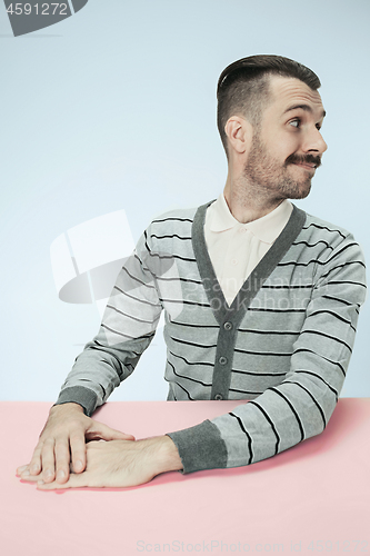 Image of The happy smiling businessman sitting at a table on a blue background