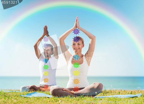 Image of couple doing yoga in lotus pose with seven chakras