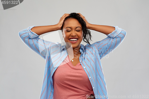 Image of happy african american woman holding to her head