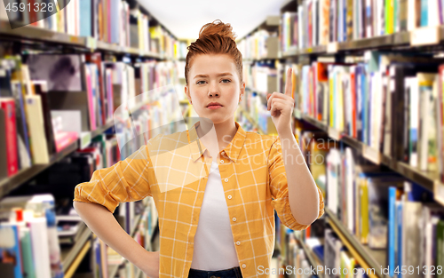 Image of serious redhead student girl warning at library