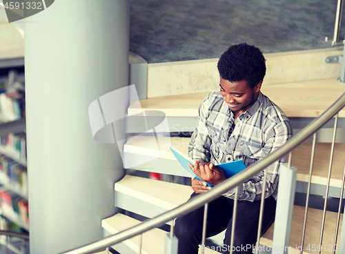 Image of african student boy or man reading book at library