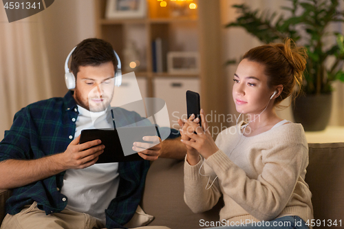 Image of couple with gadgets listening to music at home