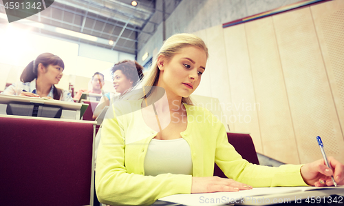 Image of student girl writing to notebook at lecture hall