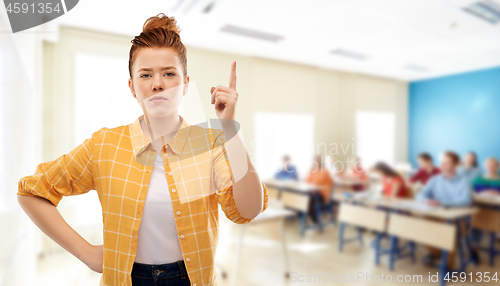 Image of red haired student girl with finger up at school